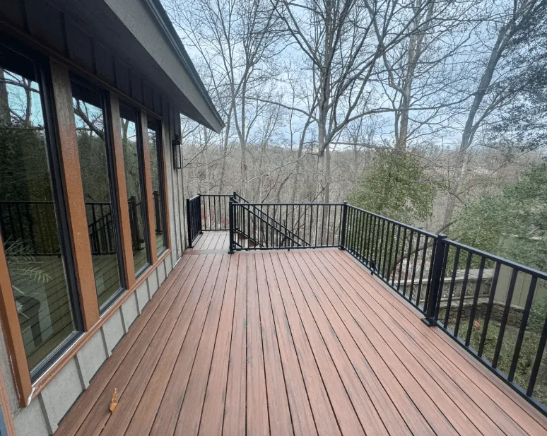 Composite deck with black aluminum railing overlooking woodland Fayetteville AR — JHG Contracting LLC