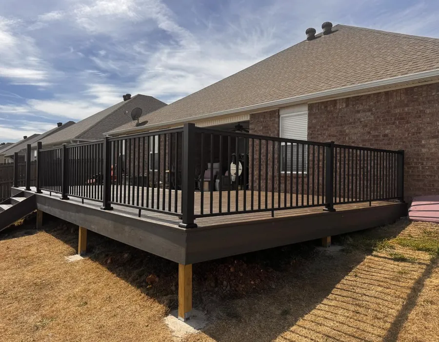 Raised TimberTech composite deck with black aluminum railing behind a brick home in Fayetteville AR — JHG Contracting LLC